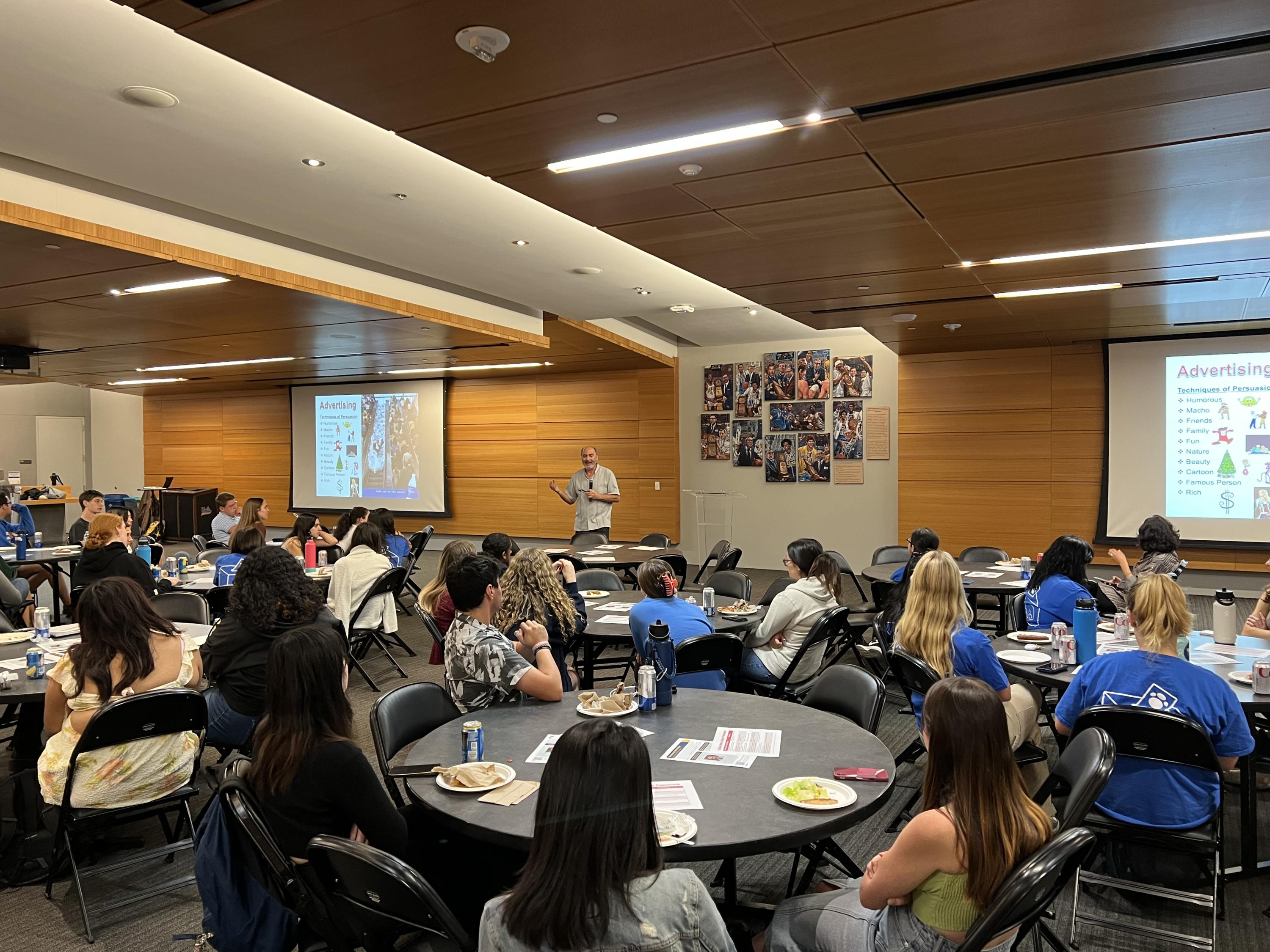 Picture of students listening to SEIS Professor Jeff Share in the Pauley Pavilion Clubhouse.